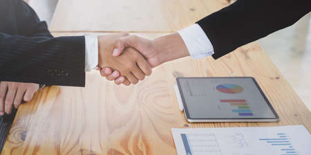 Close-up view of professional businessman shaking hands together in meeting roomの写真素材
