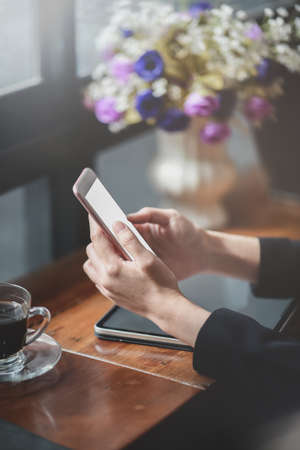 Cropped view of young businesswoman holding blank screen smartphone in comfortable working spaceの写真素材