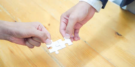 Close-up view of businesspeople solving jigsaw puzzle represent team work and cooperationの写真素材