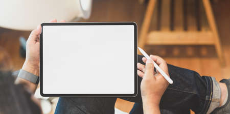 Young male freelancer holding blank screen tablet in comfortable workplaceの写真素材