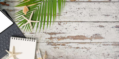 Top view of beach concept workplace with notebook, tablet and shell decoration on old wooden deskの写真素材