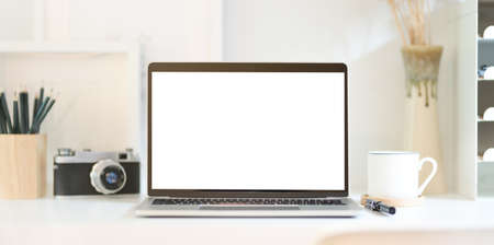 Professional photographer's workplace with open blank screen laptop, vintage camera and office...