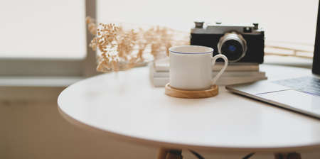 A cup of coffee and vintage camera with office supplies in comfortable corner roomの写真素材