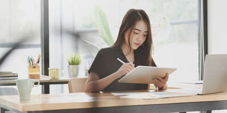 Young motivated female freelancer writing her idea in modern officeの写真素材