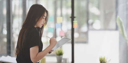 Young professional female freelancer collecting the idea from sticky notes in modern officeの写真素材