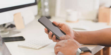 Close-up view of man holding smartphone in modern office styleの写真素材