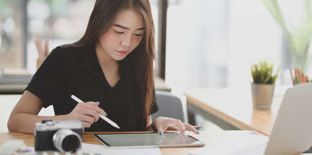 Young professional female designer working on her project in comfortable officeの写真素材