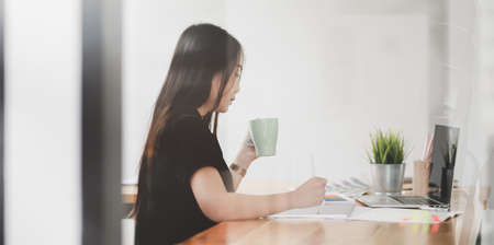 Young female designer relaxing at her workplace while working on her projectの写真素材