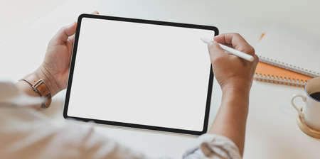 Cropped view of man using blank screen tablet in modern office with office supplies on white deskの写真素材