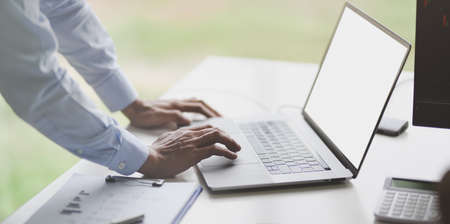 Close-up view of young businessman typing on laptop computer in modern officeの写真素材