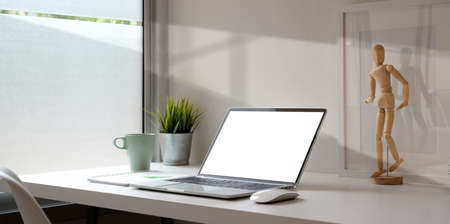 Open blank screen laptop with sticky note note, office supplies and decorations on white table