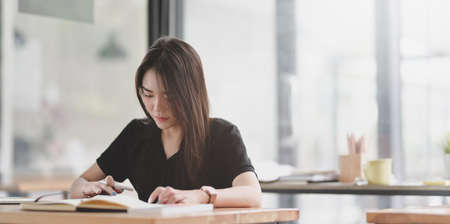 Attractive young female graphic designer reading and working on her project in modern work spaceの写真素材