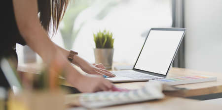 Close-up view of motivated female graphic designer working on the upcoming project with blank screen laptopの写真素材