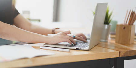 Cropped view of female graphic designer working with laptop computer at comfortable workplaceの写真素材