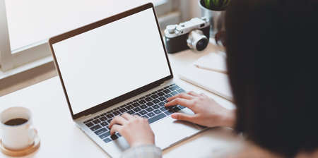 Cropped view of young businesswoman typing on blank screen laptop in modern workplaceの写真素材