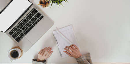 Top view of businesswoman planing her project while using laptop computer on white desk backgroundの写真素材