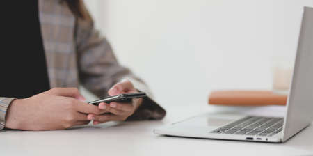 Young businesswoman searching for information on smartphone for her projectの写真素材