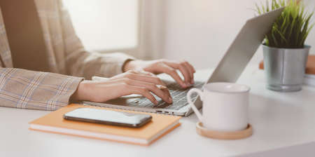 Close-up view of businesswoman typing on laptop computer while working in the modern officeの写真素材