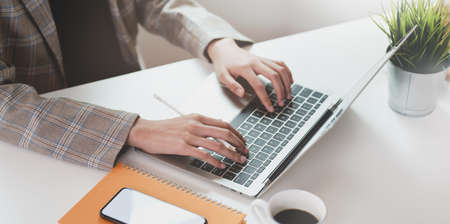 Cropped view of businesswoman typing on laptop computer while working on the projectの写真素材