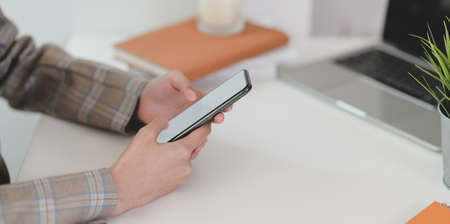 Close-up view of young businesswoman checking details on smartphone in the office roomの写真素材