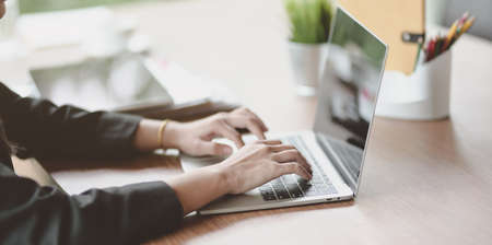 Cropped view of businesswoman typing on keyboard laptop in modern workplaceの写真素材