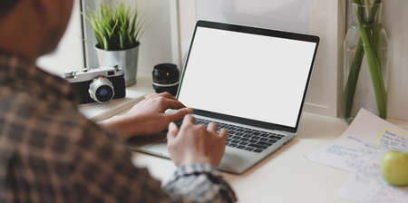 Close-up view of photographer typing on blank screen laptop computer about the current projectの写真素材
