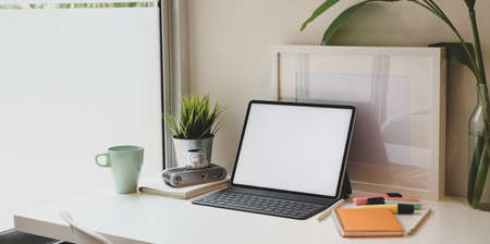 Minimal workplace with blank screen tablet, cup of coffee and office supplies on white tableの写真素材