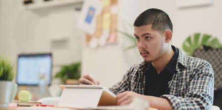 Young smart graphic designer working on the project while using tabletの写真素材
