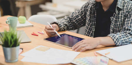 Young motivated graphic designer planing his project on tablet in comfortable workplaceの写真素材