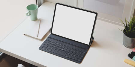 Minimal comfortable workplace with blank screen tablet and cup of coffee on white tableの写真素材