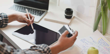 Close-up of young designer planing his idea on tablet while holding the camera in modern office roomの写真素材