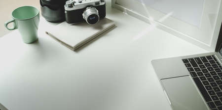 Trendy photographer workplace with tablet and vintage camera on white tableの写真素材