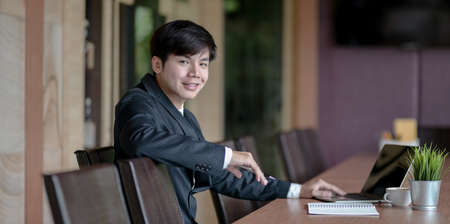 Attractive young asian businessman smiling and looking at the camera in the meeting roomの写真素材