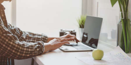Close-up view of male designer working on his project while typing on laptop computerの写真素材