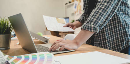 Close-up view of young graphic designer working on his project in modern workplaceの写真素材