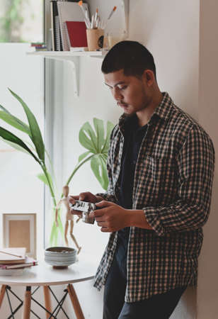 Young motivated photographer looking at the camera while working on his projects in minimal workplaceの写真素材