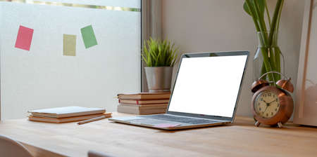 Minimal workplace with open blank screen laptop with copy space and office suppliesの写真素材