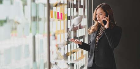 Beautiful Asian businesswoman speaking on the phone with her boss in the office roomの写真素材