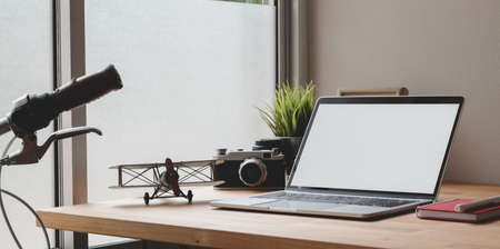 Cozy photographer home-office with open blank screen laptop, vintage camera and office decorations...
