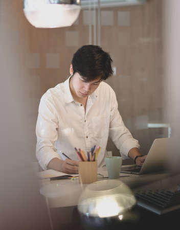 Young attractive businessman working on his project with laptop in modern office room
