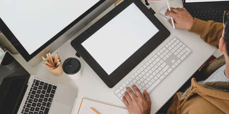 Top view of professional male designer working on his project while typing on keyboard in modern workplaceの写真素材