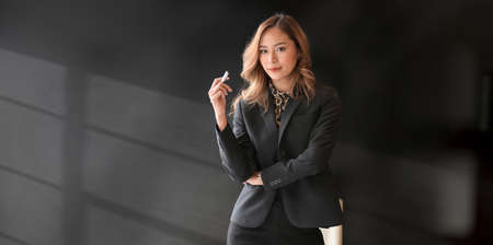 Beautiful Asian businesswoman looking at the camera confidently in the modern office roomの写真素材