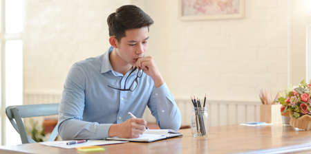 Young professional businessman writing his idea about the upcoming project in notebookの写真素材