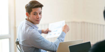 Young professional businessman looking at the camera while working with his project in modern office roomの写真素材