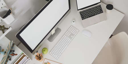 Top view of graphic designer workplace with blank screen laptop and desktop computer and copy spaceの写真素材