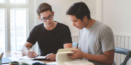 Two young startup member discussing the project together with books in comfortable workplaceの写真素材