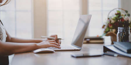 Close-up view of professional businesswoman typing on laptop keyboard while working in the officeの写真素材