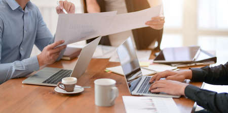 Professional business team working on their project together in the meeting room while using laptop...