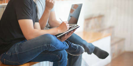 Close-up view of young men discussing the group projects together while using laptop computer and tabletの写真素材