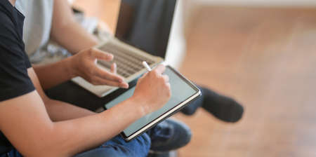 Close-up view of young men discussing the group projects together while using laptop computer and tabletの写真素材
